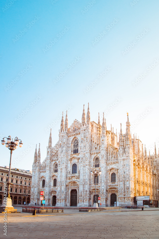 View of Milan Cathedral (Duomo di Milano) with empty square due to coronavirus lockdown (red zone), side illuminated by the sun, vertical