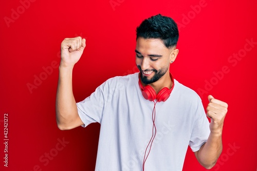 Young man with beard listening to music using headphones dancing happy and cheerful, smiling moving casual and confident listening to music