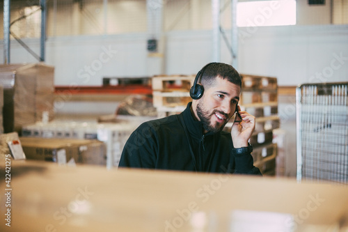 Male manual worker talking through headset at logistics warehouse