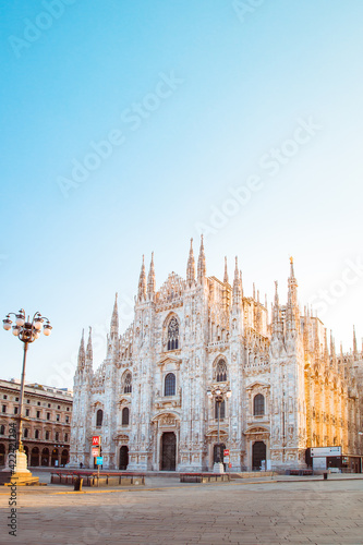 View of Milan Cathedral (Duomo di Milano) with empty square due to coronavirus lockdown (red zone), side illuminated by the sun, vertical