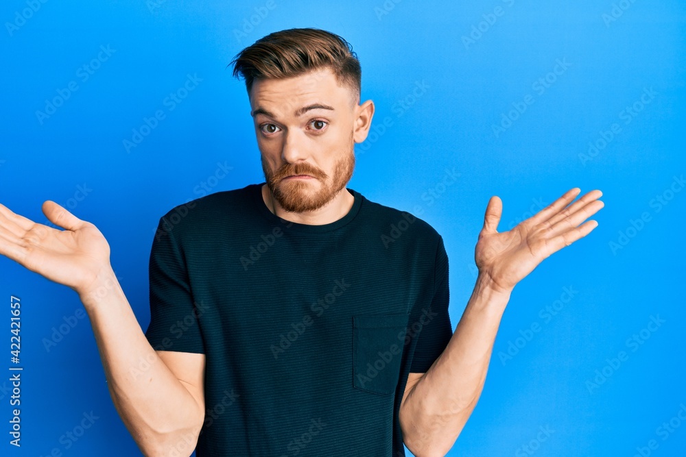 Young redhead man wearing casual black t shirt clueless and confused with open arms, no idea and doubtful face. Young redhead man wearing casual black t shirt clueless and confused with open arms, no idea and doubtful face.