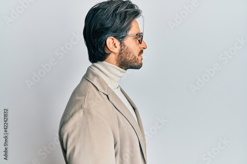 Young hispanic man wearing business jacket and glasses looking to side, relax profile pose with natural face with confident smile.