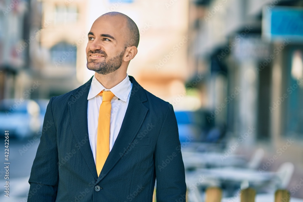 Young hispanic bald businessman smiling happy standing at the city.