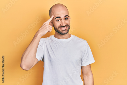 Young bald man wearing casual white t shirt smiling pointing to head with one finger, great idea or thought, good memory © Krakenimages.com