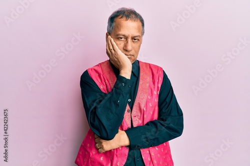 Middle age indian man wearing traditional indian clothes thinking looking tired and bored with depression problems with crossed arms.