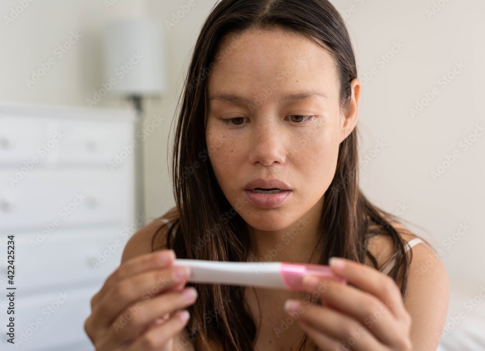 A shocked surprised woman looking at a positive pregnancy test. A shocked surprised woman looking at a positive pregnancy test.