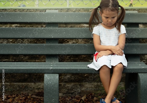 A depressed sad frustrated little girl sitting alone. Social anxiety and stressed children.