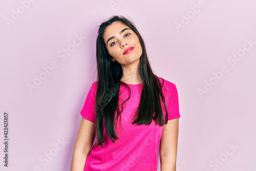 Young hispanic girl wearing casual pink t shirt relaxed with serious expression on face. simple and natural looking at the camera.