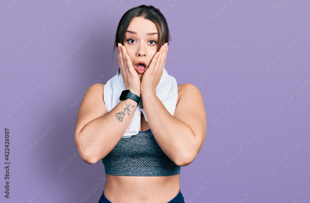 Young hispanic girl wearing sportswear and towel afraid and shocked, surprise and amazed expression with hands on face Young hispanic girl wearing sportswear and towel afraid and shocked, surprise and amazed expression with hands on face