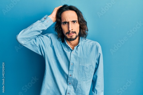 Young hispanic man wearing casual clothes confuse and wonder about question. uncertain with doubt, thinking with hand on head. pensive concept. © Krakenimages.com