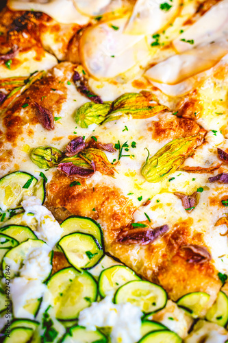 Close up of many pizza slices of different kinds. Zucchini and mozzarella, ham, anchovies, courgette flower. photo