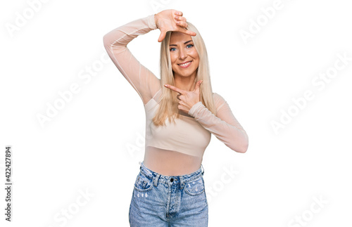 Young blonde woman wearing casual clothes smiling making frame with hands and fingers with happy face. creativity and photography concept.