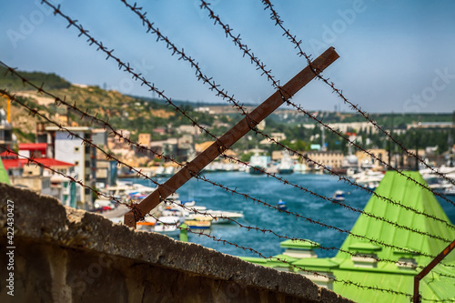 Fototapeta Concept view of Balaklava bay with yachts in Sevastopol city through the barbed wire