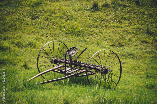 Scenic green landscape with old altaic horse plow with saddle in field among lush grasses. Minimalist vivid green scenery with iron horse old plow on background of grassy hill close up. Rustic plow. photo