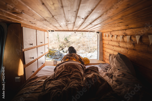 Vanlife - Young woman lying in camping van and looking at beautiful nature