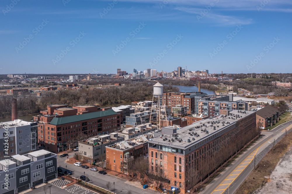 Aerial panorama view of Rocketts Landing near Richmond Virginia, regentrified industrial shopping complex with luxury apartments in former warehouses, water tower along the James river with blue sky