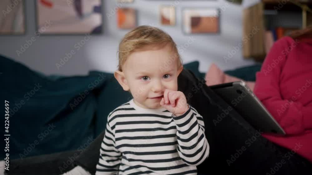 Close-up of happy little boy in striped shirt. Portrait of thinking child, kid is sitting on sofa near mom. Having fun together with mother, tickling. Close-up of happy little boy in striped shirt. Portrait of thinking child, kid is sitting on sofa near mom. Having fun together with mother, tickling.