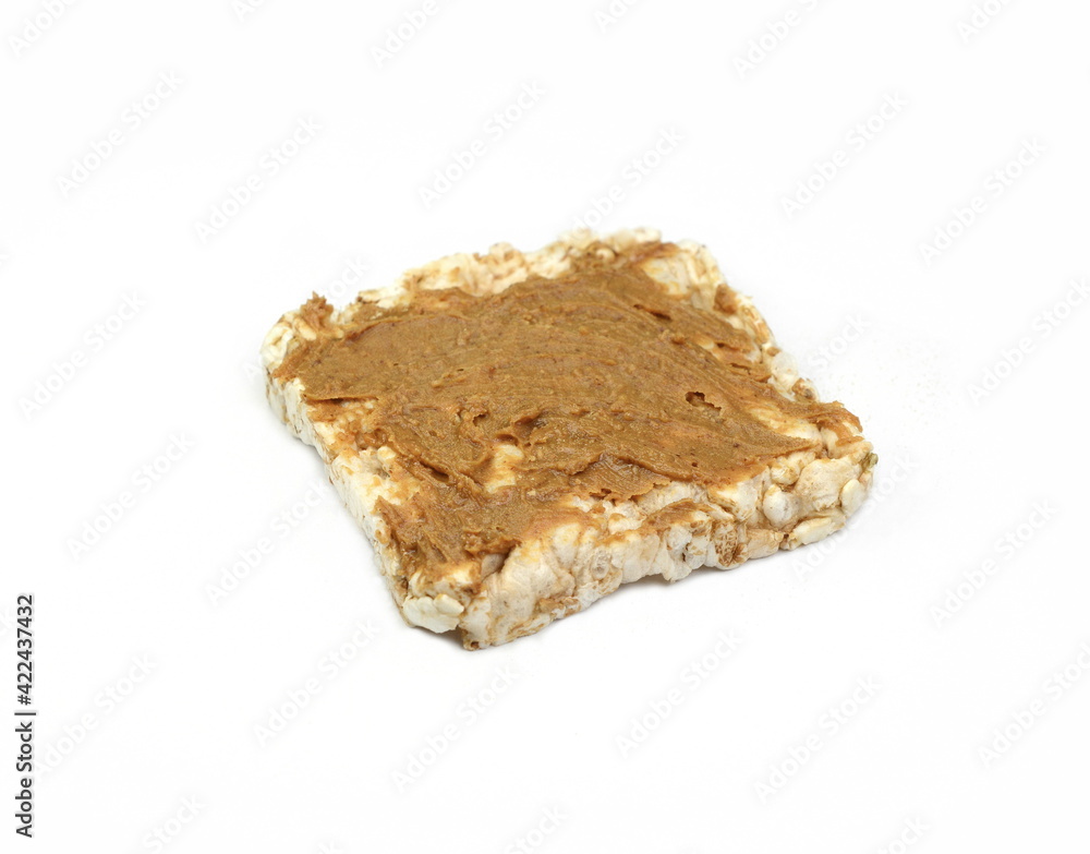 Puffed rice cakes smeared with peanut butter isolated on white. Stack of puffed whole grain crispbread isolated on white. Puffed rice cakes smeared with peanut butter isolated on white. Stack of puffed whole grain crispbread isolated on white.
