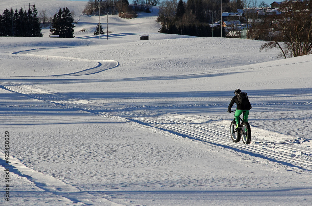 Ein Radfahrer fährt im Winter durch den Schnee