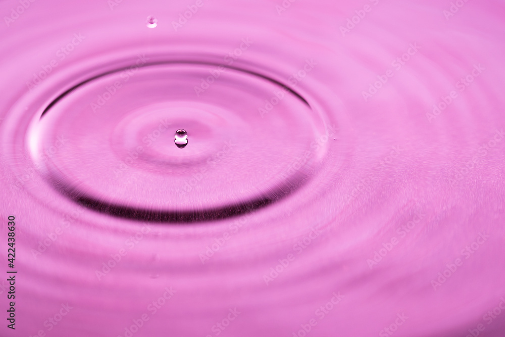 Macro shot of a water drop with pink hues Macro shot of a water drop with pink hues
