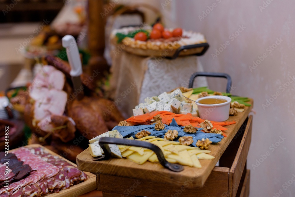 Serving wooden desk with various cheeses on the party on the meat food background.