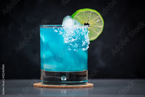 Blue Margarita on the rocks with salted rim and a lime wheel