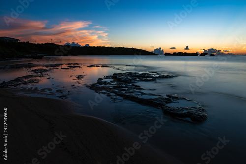 .Long exposure scene of Hoshizuna beach after sunset. Colorful clouds reflecting in the water. Rock platform mixing with moist sands  smooth surface sea bringing calm and tranquility to the view.
