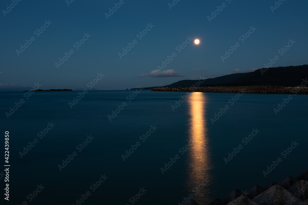 Fototapeta premium Beautiful twilight with the moon rising reflecting in the sea and mountain behind composing the beautiful view. Iriomote Island.