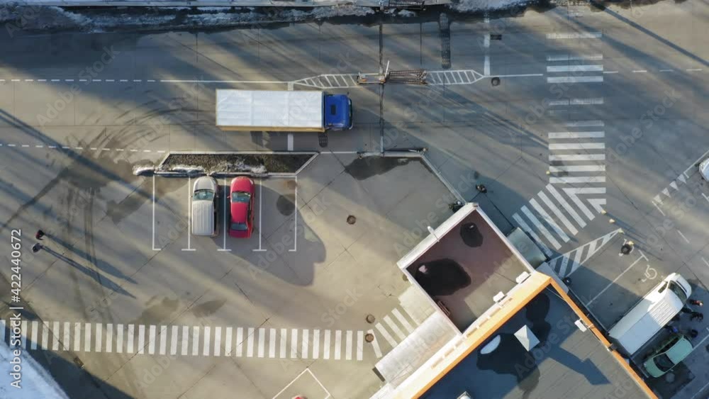 Aerial top down view of a semi-trailer truck is travelling along a warehouse in a logistic park with loading hub Aerial top down view of a semi-trailer truck is travelling along a warehouse in a logistic park with loading hub