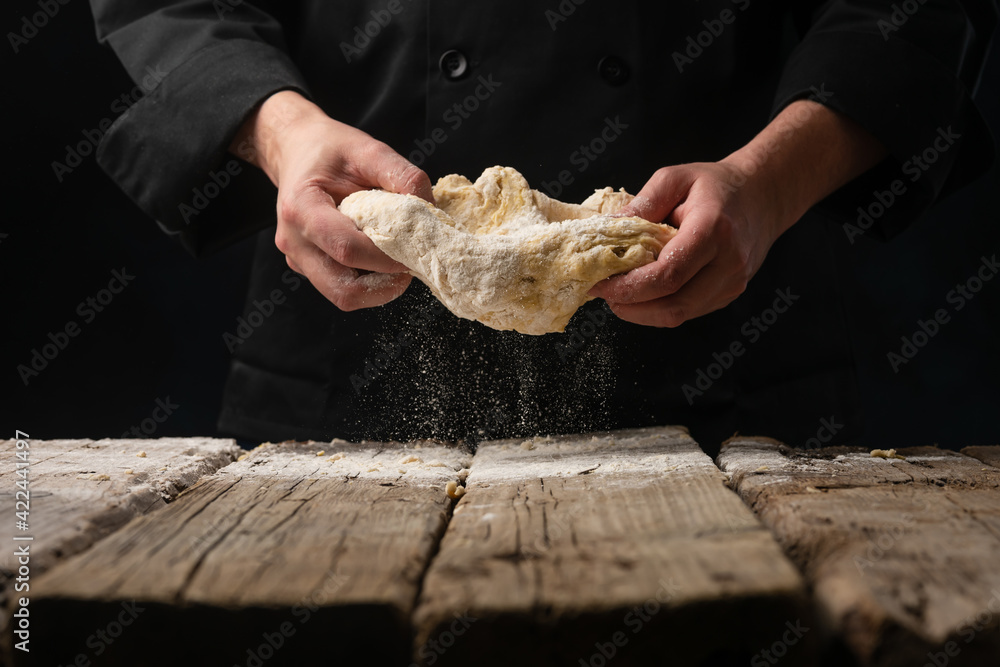 The chef prepares the dough. Works with flour, freeze in motion.Cooking baking bread, pizza and italian pasta.Culinary recipes on a black background