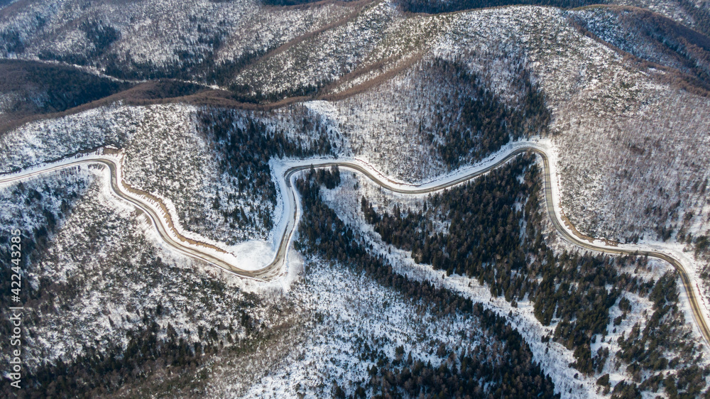 Aerial view of the river and taiga forests and road in the winter - springtime . Abstract landscape of northern nature with drone.