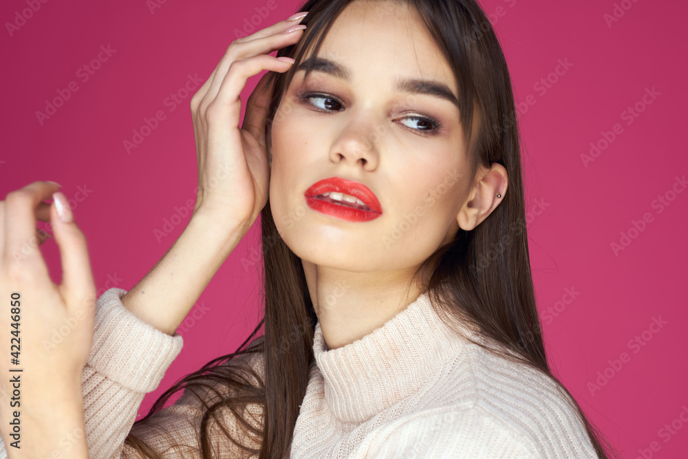Fototapeta premium Brunette with long hair red lips cosmetics white sweater pink background cropped view
