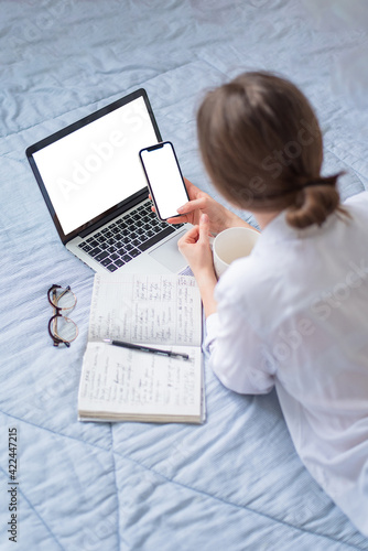 Back view of a freelancer girl working on a new project on a laptop with a blank copy of the screen space for your promotional text message, working from home