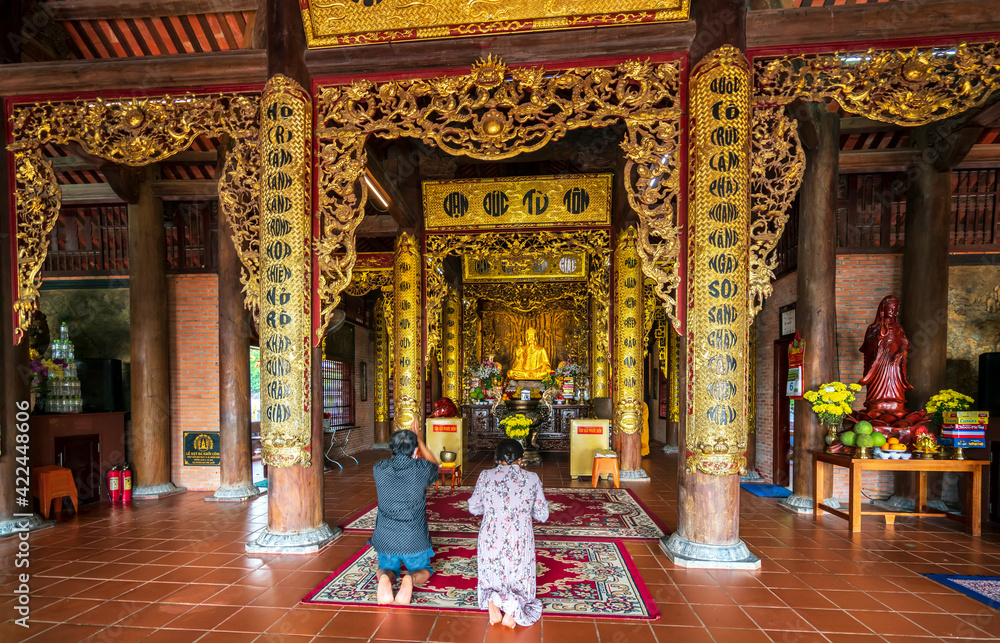 Couple praying for family peace in Ho Quoc temple on the morning of the full moon day on the beautiful island of Phu Quoc, Vietnam