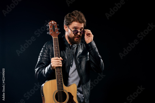 A man with a guitar in his hands leather jacket music performance rock star modern style dark background