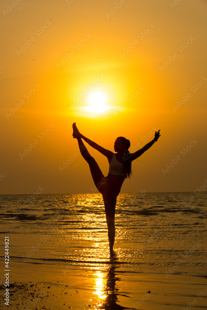 silhouette of a woman during yoga improve inner harmony, healthy lifestyle, mind body relaxation concept on the beach at sunset