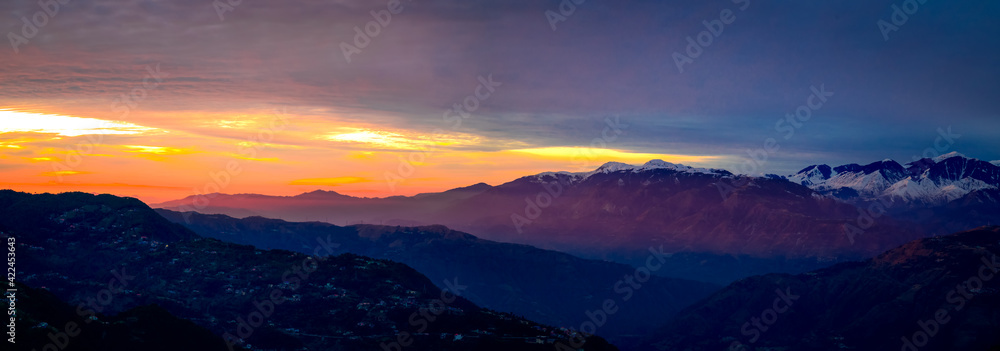Panoramic view of sunrise over the mountains. Colourful, vibrant, burning sunset, skies, dramatic clouds over the Himalayan mountains. On Trek to Dalhousie, Himachal Pradesh, India.	