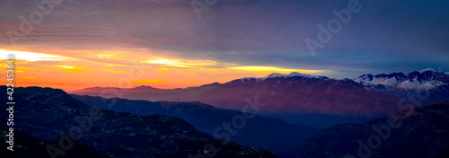 Panoramic view of sunrise over the mountains. Colourful, vibrant, burning sunset, skies, dramatic clouds over the Himalayan mountains. On Trek to Dalhousie, Himachal Pradesh, India. 