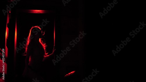 Slender girl in red light waving her hair.