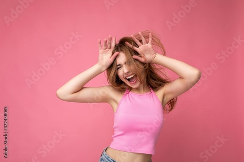 Crazy young attractive blonde woman with sincere emotions isolated on background wall with copy space wearing stylish pink top. Positive concept