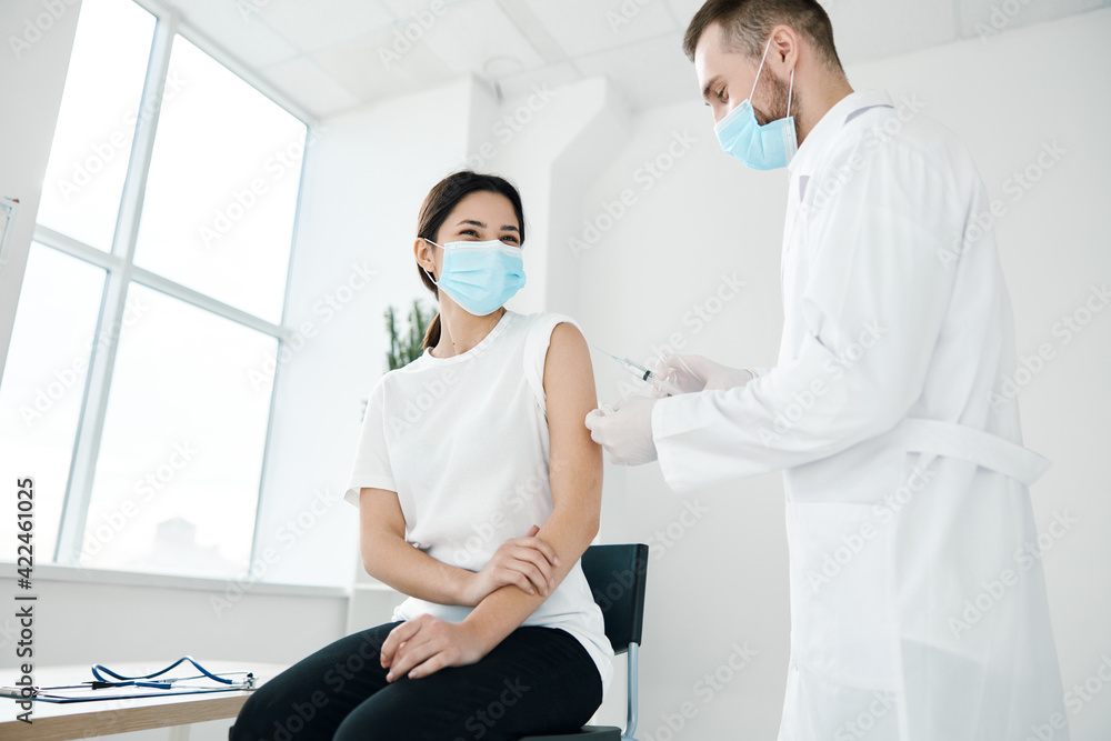 Obraz premium doctor in a medical gown and a woman in a protective mask covid-19 vaccination coronavirus
