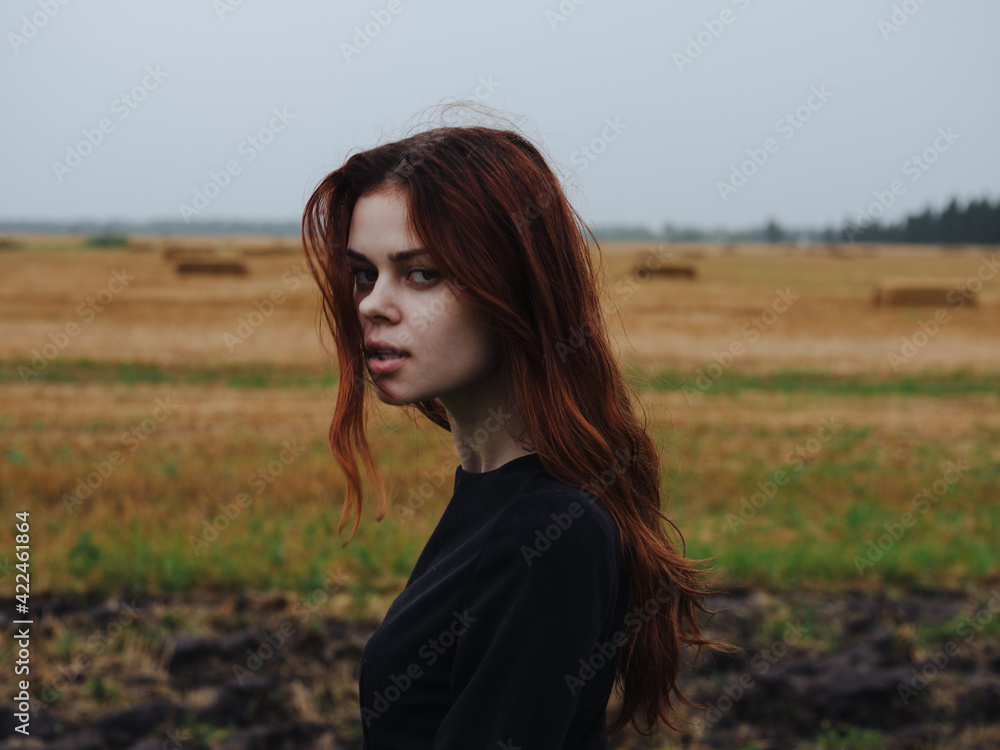 Beautiful woman with red hair in a black dress outdoors in the field Beautiful woman with red hair in a black dress outdoors in the field