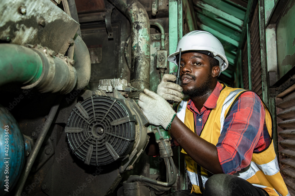 Handsome Africa American industrial engineering are plan and discussing engines in train station garage plants with walkie takie. Engineer and repair man concept. Safety first Handsome Africa American industrial engineering are plan and discussing engines in train station garage plants with walkie takie. Engineer and repair man concept. Safety first