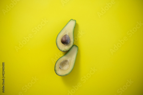 Food background with fresh organic avocado on yellow background. top view, two halves