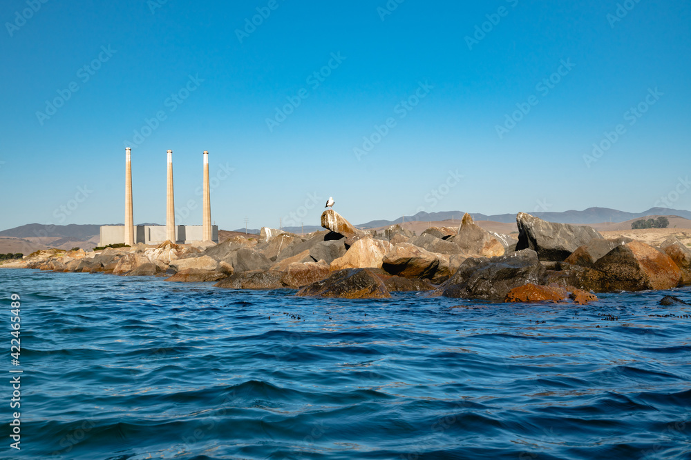 Rocky beach and an old power plant whose three large smokestacks can be seen from anywhere in Morro Bay, California