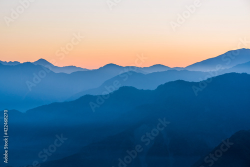 Layers of magnificent mountains with colorful clouds background at sunrise view © BINGJHEN