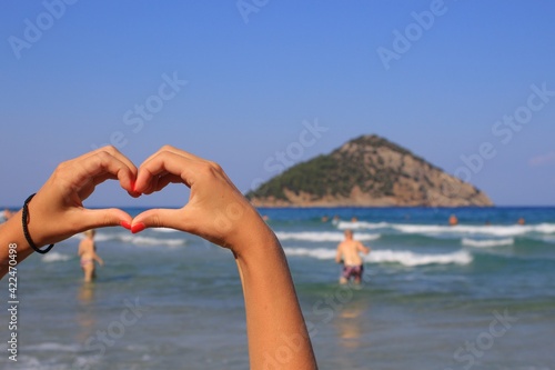 hands heart on the beach with island and sea in background