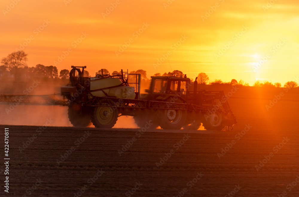 agricultural tractor with sprayer on the field during sunset agricultural tractor with sprayer on the field during sunset