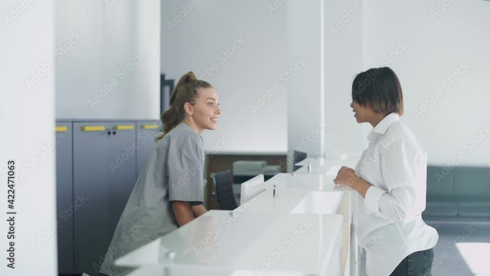 Hospital reception, a nurse registers an young woman patient for a doctor's appointment in a modern medical clinic, the woman signs the documents. Hospital reception, a nurse registers an young woman patient for a doctor's appointment in a modern medical clinic, the woman signs the documents.