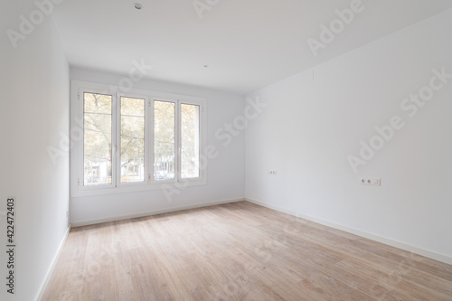 Empty dusted room after renovation with white walls  windows and wooden floor.